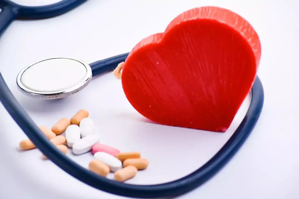 A clean, well-lit tabletop scene displaying an assortment of common myocardial infarction medications. In the foreground, various pill bottles and blister packs are arranged neatly, their labels and colors clearly visible. In the middle ground, a stethoscope and a medical chart partially obscure the medications, hinting at their clinical context. The background features a soft, out-of-focus medical setting, perhaps a hospital room or doctor's office, to establish the appropriate mood and atmosphere. The overall lighting is warm and natural, creating a sense of reassurance and professionalism. The composition and camera angle convey a sense of authoritative knowledge about these essential post-MI treatments.