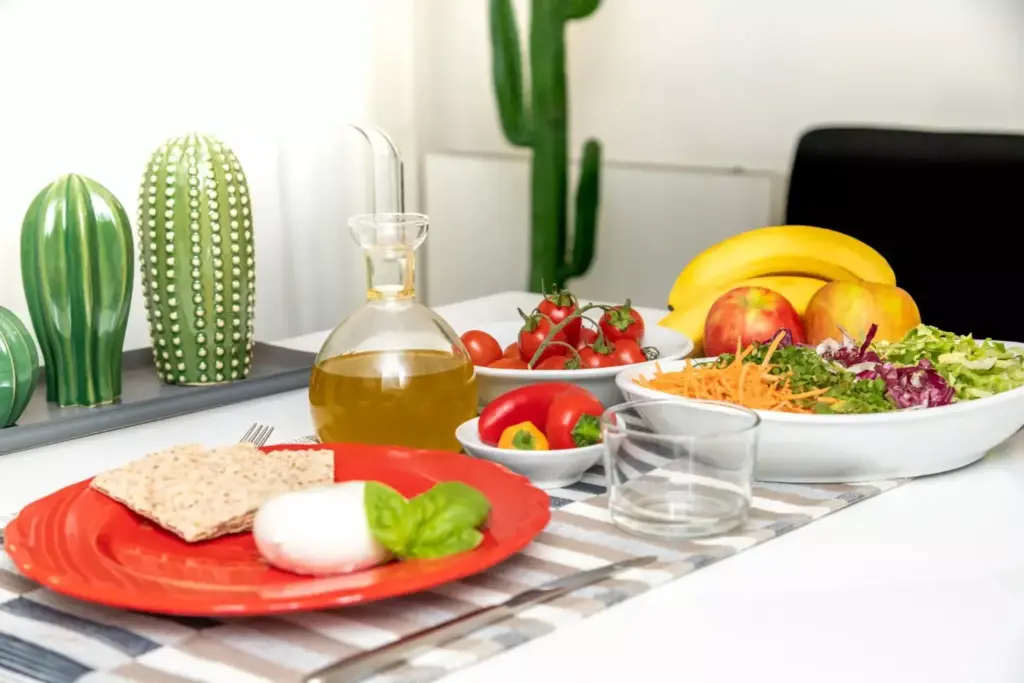 A cozy kitchen scene with a stack of soft, nourishing foods on a wooden table. In the foreground, a plate showcases a variety of easily digestible ingredients - steamed vegetables, lean proteins, and whole grains. Soft lighting from a nearby window casts a warm glow, creating a calming, comforting atmosphere. In the background, kitchen utensils and appliances suggest a well-equipped space for preparing a post-surgery recovery diet. The overall composition emphasizes the importance of a thoughtfully curated, nutritious meal plan during the healing process after prostate surgery.