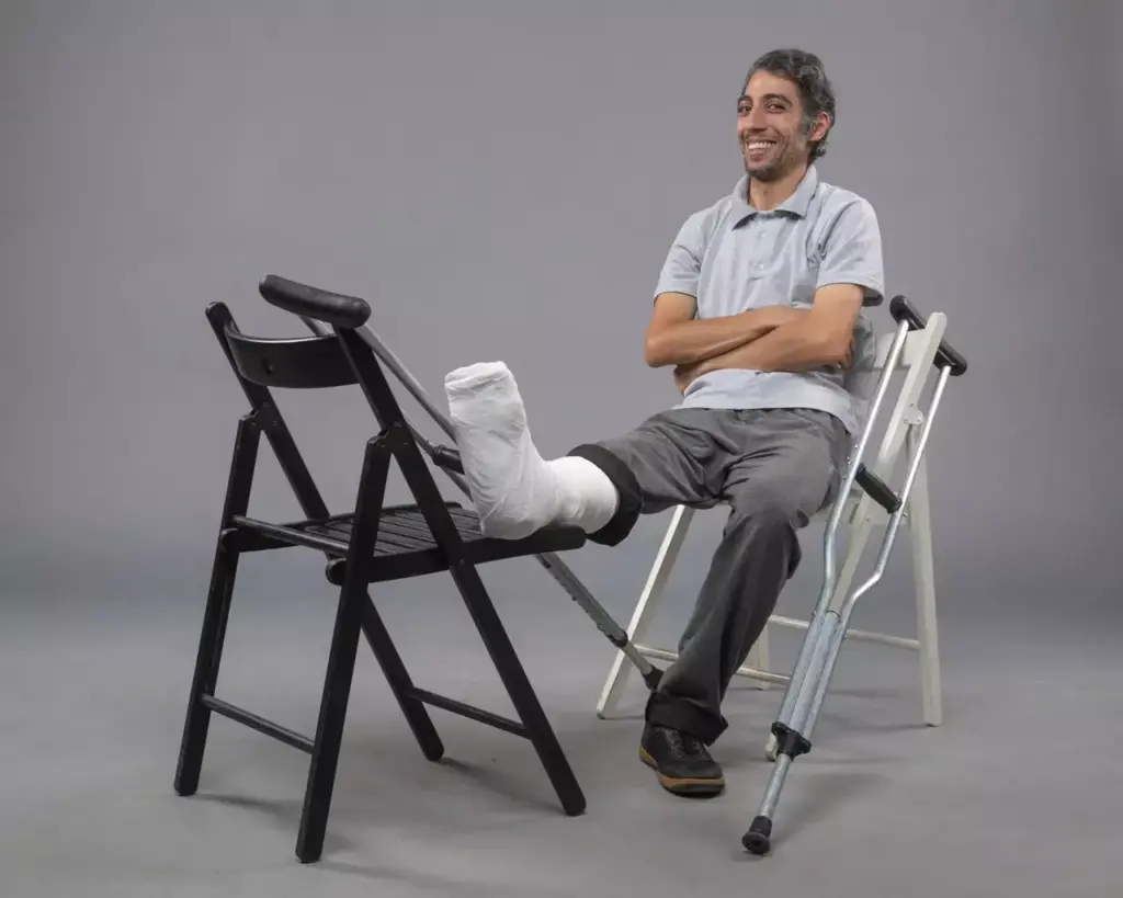 A patient sitting comfortably on a chair, leg propped up on a stool, with a knee brace visible. The background is a modern, light-filled physical therapy clinic, with clean white walls and equipment visible. The lighting is soft and diffuse, creating a serene and calming atmosphere. The subject's expression conveys a sense of cautious optimism as they begin their knee replacement recovery journey. The scene is captured using a wide-angle lens, providing a comprehensive view of the recovery process. A patient sitting comfortably on a chair, leg propped up on a stool, with a knee brace visible. The background is a modern, light-filled physical therapy clinic, with clean white walls and equipment visible. The lighting is soft and diffuse, creating a serene and calming atmosphere. The subject's expression conveys a sense of cautious optimism as they begin their knee replacement recovery journey. The scene is captured using a wide-angle lens, providing a comprehensive view of the recovery process.