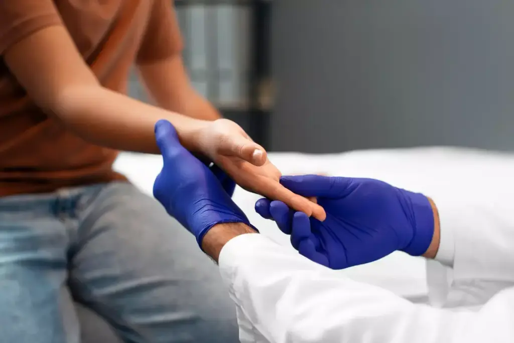 Detailed cross-section illustration of a carpal tunnel release surgery procedure. The foreground depicts the surgeon's hands delicately operating on the exposed wrist, carefully severing the transverse carpal ligament to relieve pressure on the median nerve. The middle ground shows the anatomy of the carpal tunnel, with the flexor tendons and median nerve clearly visible. The background features a dimly lit operating room with medical equipment and lighting creating a somber, clinical atmosphere. Rendered in a precise, technical style with high-contrast lighting to emphasize the intricate details of the surgical intervention.