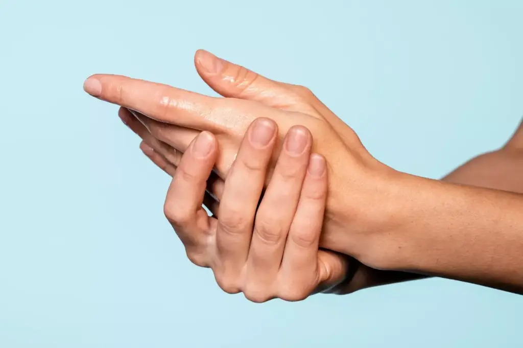 A close-up view of a human hand displaying symptoms of carpal tunnel syndrome. The hand is positioned on a plain, neutral-colored background, with the wrist and palm prominently featured. The fingers are slightly bent, and the palm shows visible signs of swelling and inflammation. The image is lit from the side, creating subtle shadows that accentuate the contours of the hand. The lighting is soft and diffused, creating a calm, clinical atmosphere. The focus is sharp, allowing for clear visualization of the affected area, while the background remains slightly blurred to draw the viewer's attention to the hand. The overall tone is informative and educational, suitable for illustrating the section on &amp;quot;What Is Carpal Tunnel Syndrome and When Surgery Becomes Necessary&amp;quot;.