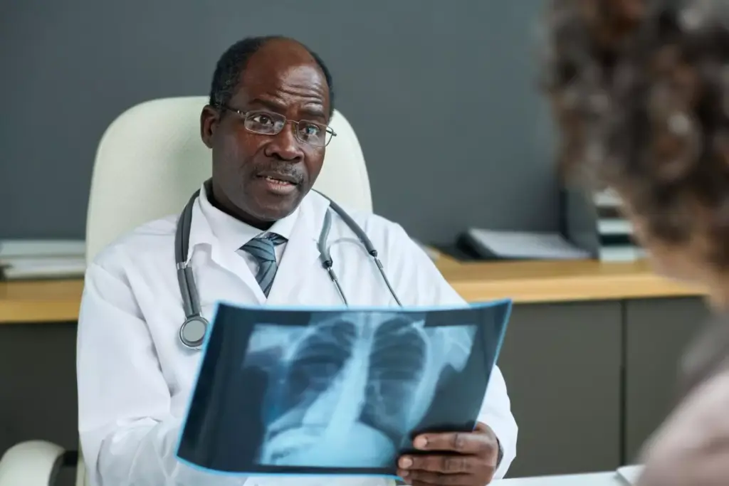 A medical examination room with a doctor reviewing a patient's chest X-ray on a light box. The doctor is wearing a white lab coat and has a serious, focused expression as they analyze the X-ray, looking for signs of squamous lung cancer. The room is well-lit with soft, warm lighting, creating a clinical yet reassuring atmosphere. In the background, various medical equipment and supplies are neatly arranged, conveying the professionalism of the healthcare setting. The composition emphasizes the doctor's attention to the diagnostic process, highlighting the importance of accurately identifying and staging advanced squamous lung cancer. A medical examination room with a doctor reviewing a patient's chest X-ray on a light box. The doctor is wearing a white lab coat and has a serious, focused expression as they analyze the X-ray, looking for signs of squamous lung cancer. The room is well-lit with soft, warm lighting, creating a clinical yet reassuring atmosphere. In the background, various medical equipment and supplies are neatly arranged, conveying the professionalism of the healthcare setting. The composition emphasizes the doctor's attention to the diagnostic process, highlighting the importance of accurately identifying and staging advanced squamous lung cancer.