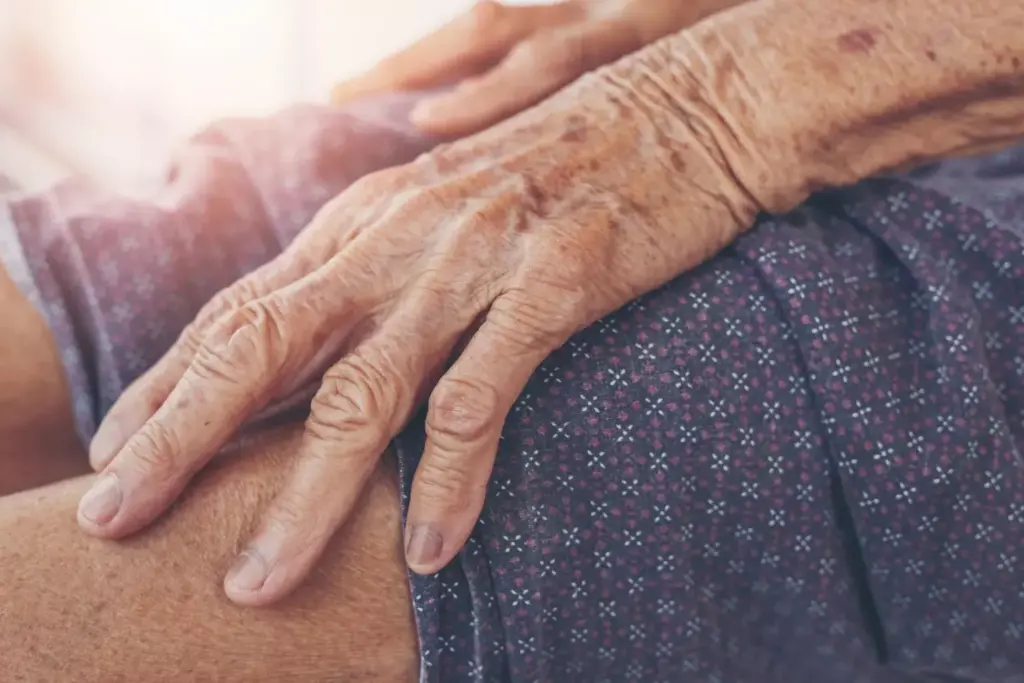 A detailed, close-up view of an elderly person's hand suffering from the swollen, inflamed joints of arthritis. The skin appears reddened and painful, with a tense, aching expression on the face. In the background, a muted, desaturated environment reflects the somber, debilitating nature of the condition. Soft, diffused lighting illuminates the hand, emphasizing the textural details and the patient's physical distress. The composition is framed to convey a sense of empathy and understanding for the challenges of living with chronic arthritic pain.