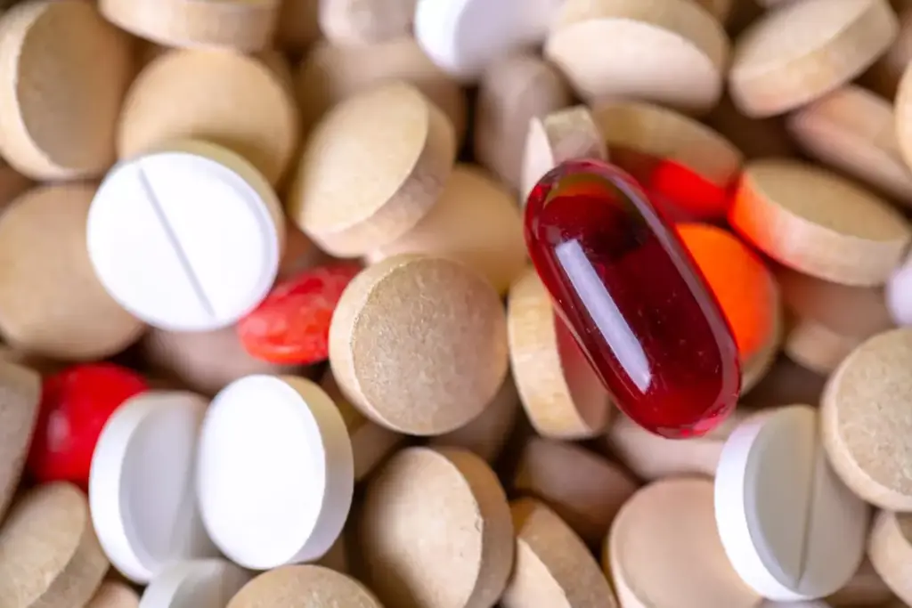 A neatly arranged still life of various over-the-counter arthritis pills and pain medications. In the foreground, a collection of colorful capsules, tablets, and gel caps in shades of white, red, and green are displayed on a clean, light-colored surface. The middle ground showcases a few recognizable brand name bottles and containers, their labels visible. The background is softly blurred, hinting at a plain, uncluttered studio setting with gentle, natural-looking lighting from the side, casting subtle shadows and highlights that accentuate the textures and shapes of the pharmaceutical products. The overall mood is one of clinical precision and informative clarity, suitable for illustrating a section on effective over-the-counter arthritis remedies.