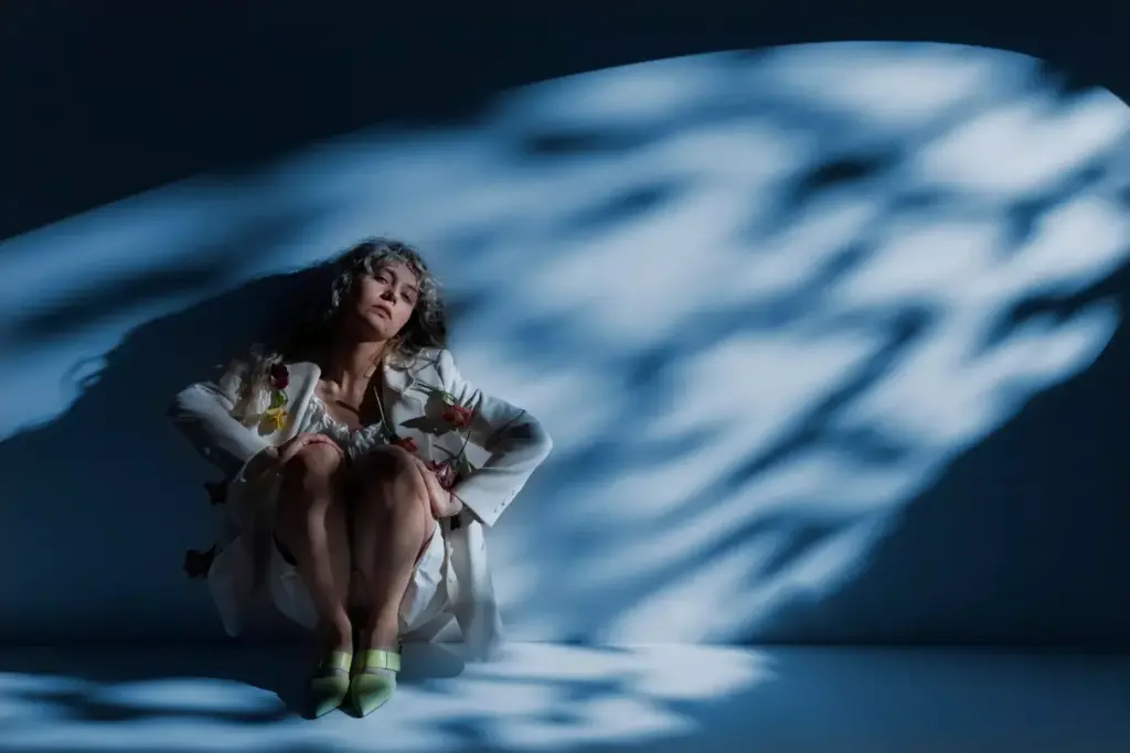 A woman sits in a dimly lit room, her face etched with weariness. A warm, golden light filters through the window, casting a soft glow on her features. Her hands gently cradle her head, as if trying to soothe the pounding ache within. The background is blurred, drawing the viewer's focus to the woman's expression of discomfort and the subtle tension in her body. The image conveys the overwhelming exhaustion and discomfort that can accompany chemotherapy-induced headaches, capturing the essence of the subject matter in a visually compelling manner.