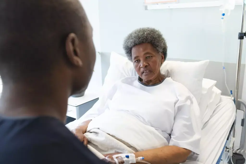African american male doctor talking with senior female patient in hospital 
