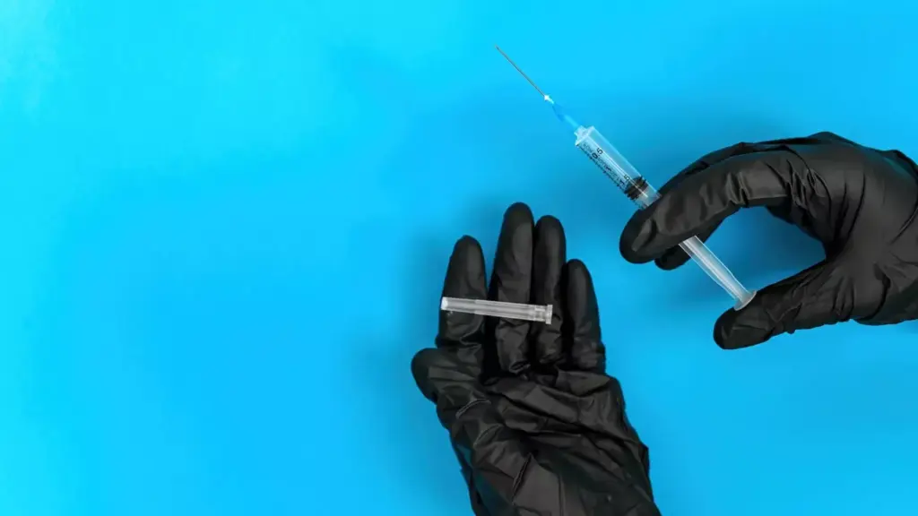 A close-up view of a person's hand holding a syringe filled with a clear, glowing liquid against a backdrop of blurred medical equipment, IV tubes, and a hospital bed. The lighting is soft and diffused, creating a contemplative, almost ethereal atmosphere. The focus is on the syringe, conveying the essence of chemotherapy treatment for lymphoma, a crucial step in the fight against this cancer.