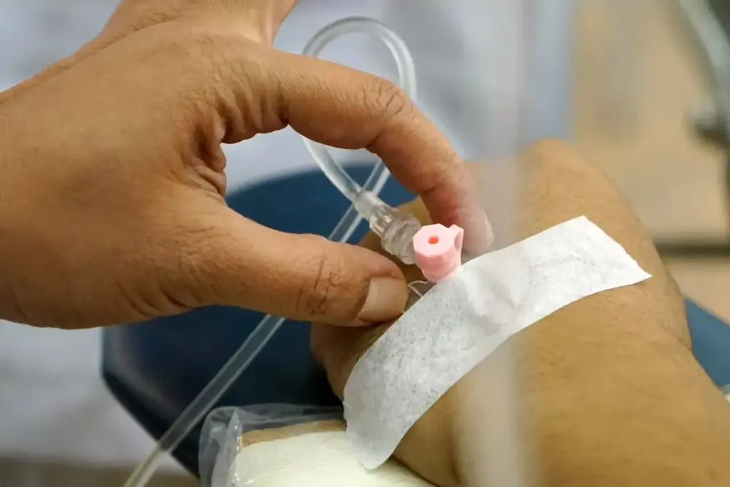 A detailed cross-section of a chemotherapy infusion process, with a central focus on the intravenous line delivering the cytotoxic medication. In the foreground, the patient's arm is gently resting, with the insertion point and tubing clearly visible. The middle ground features the infusion pump, its digital display and controls, conveying a sense of precision and monitoring. The background showcases the medical equipment and environment, such as an IV pole, medical cabinets, and subtle lighting that creates a calm, sterile atmosphere. The overall composition emphasizes the technical yet delicate nature of the chemotherapy administration, reflecting its vital role in cancer treatment.