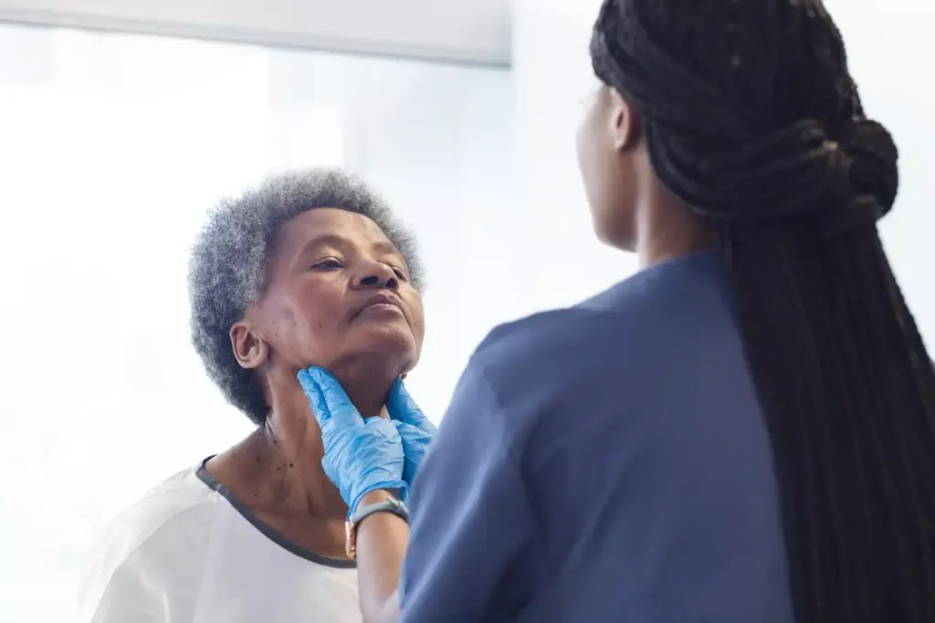 African american female doctor testing neck of senior female patient in hospital