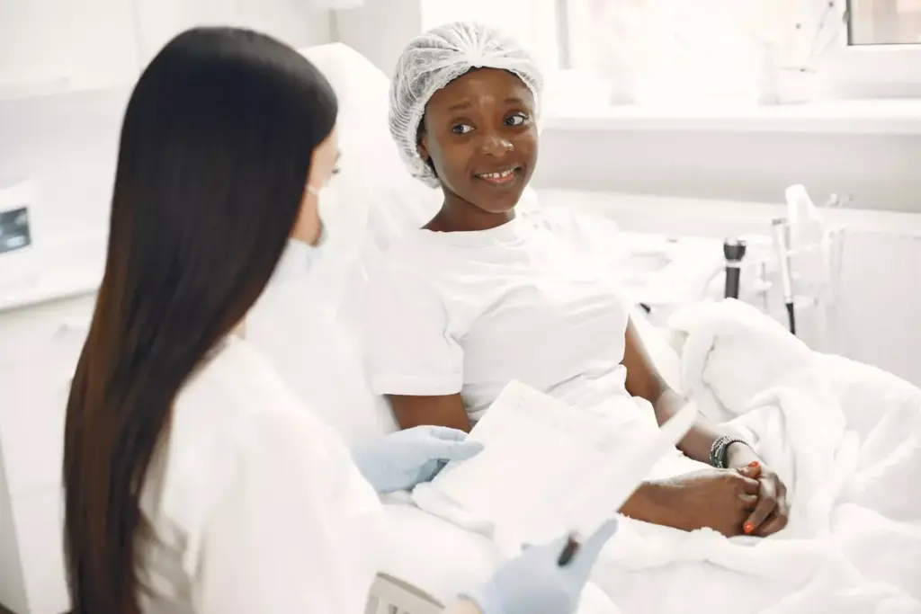 A serene hospital ward bathed in soft, warm lighting. In the foreground, a group of women gather in a supportive embrace, their faces reflecting understanding and empathy. In the middle ground, medical professionals in white coats move with quiet efficiency, their expressions conveying compassion. In the background, a panoramic window offers a glimpse of a verdant landscape, symbolizing the resilience and hope that permeates this space of healing. The overall atmosphere is one of unity, care, and the unwavering strength of the breast cancer community.