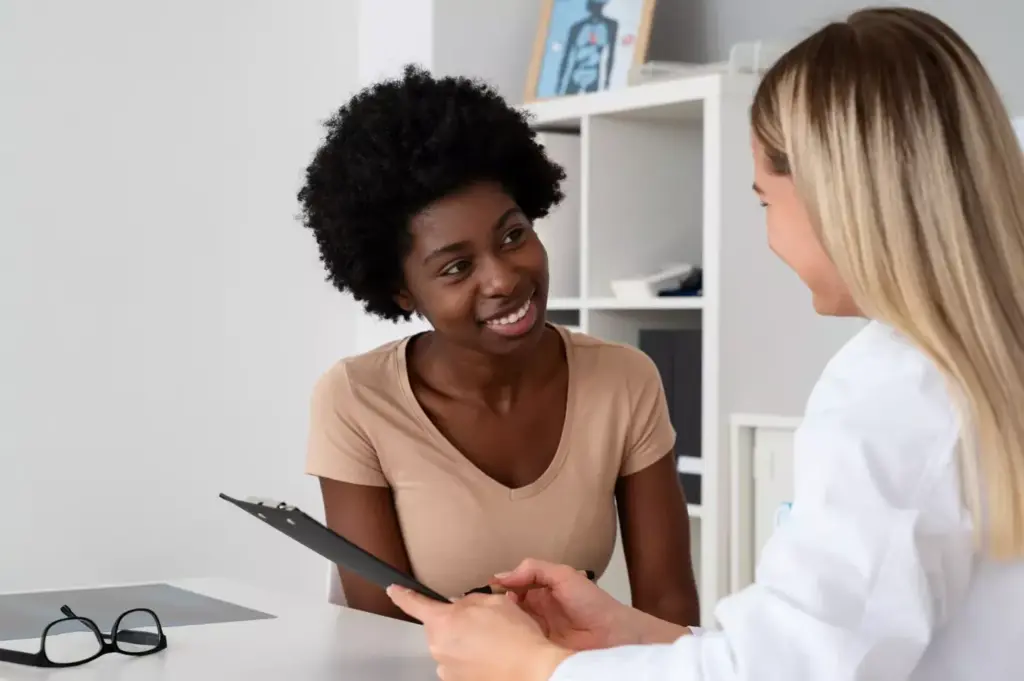A compassionate woman offers financial guidance and support to a breast cancer patient, sitting together in a cozy, well-lit office. Warm lighting illuminates their faces as they review paperwork, discussing options for medical expenses and treatment costs. The background is softly blurred, focusing attention on their collaborative, empathetic interaction. The scene conveys a sense of care, understanding, and the vital importance of financial assistance during the difficult breast cancer journey. A compassionate woman offers financial guidance and support to a breast cancer patient, sitting together in a cozy, well-lit office. Warm lighting illuminates their faces as they review paperwork, discussing options for medical expenses and treatment costs. The background is softly blurred, focusing attention on their collaborative, empathetic interaction. The scene conveys a sense of care, understanding, and the vital importance of financial assistance during the difficult breast cancer journey.