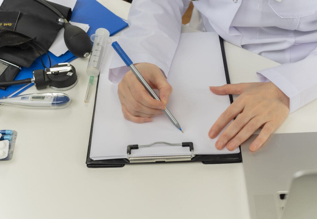 cropped shot female doctor hands working desk with medical tools laptop writing prescription clipboard LIV Hospital
