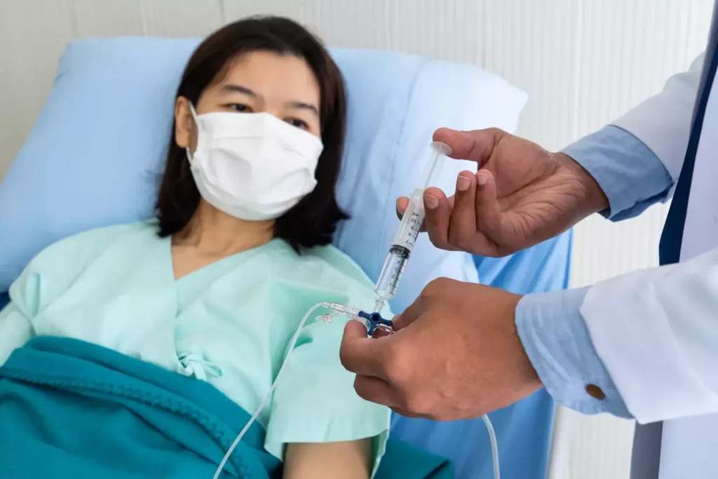 a doctor or nurse in sterile attire holds a syringe filled with a clear liquid, representing the BCG (Bacillus Calmette-Guérin) therapy for bladder cancer. The middle ground features a patient in a reclined position