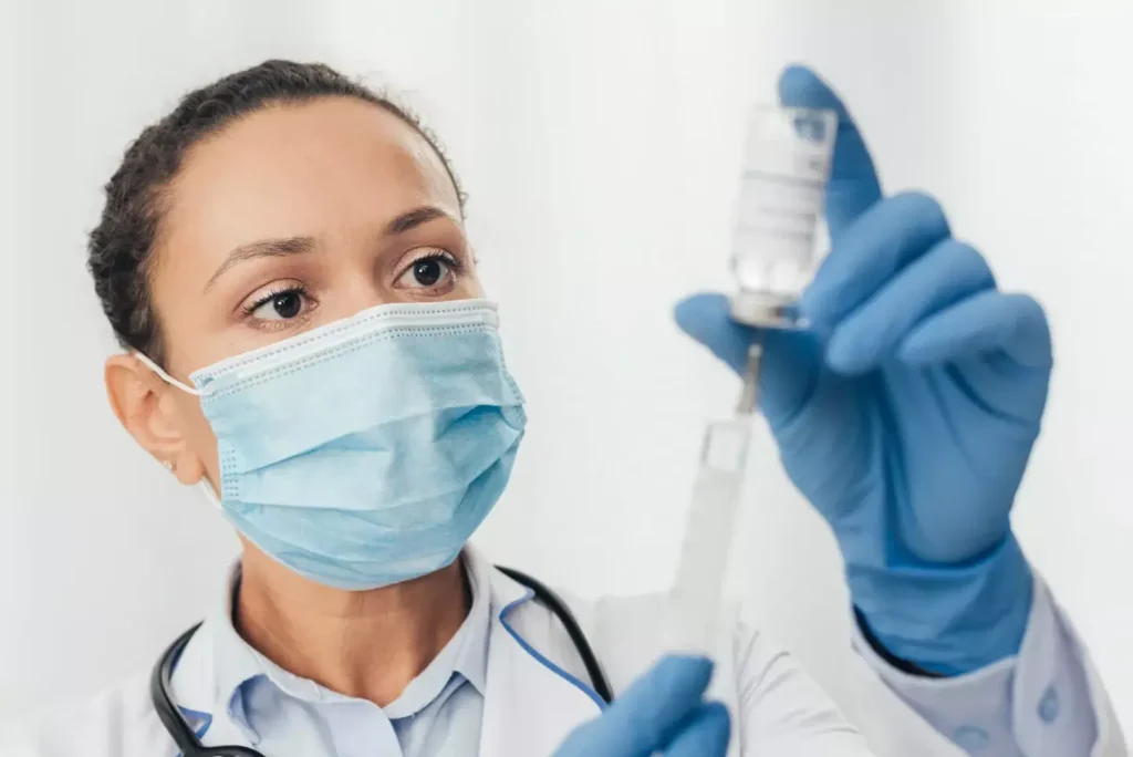 a doctor in a white coat is carefully preparing a syringe, their expression focused and professional