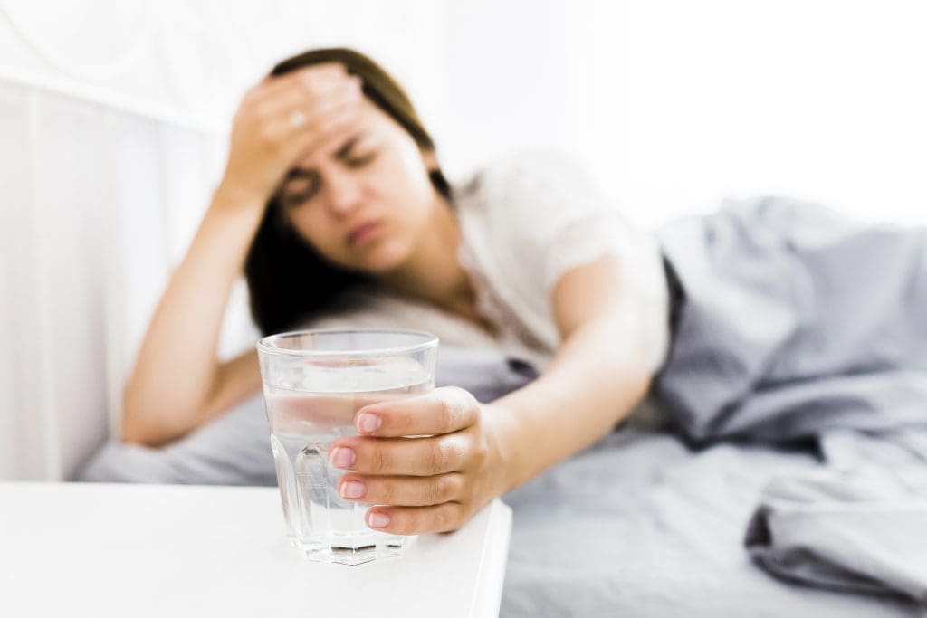 woman with headache taking glass water LIV Hospital