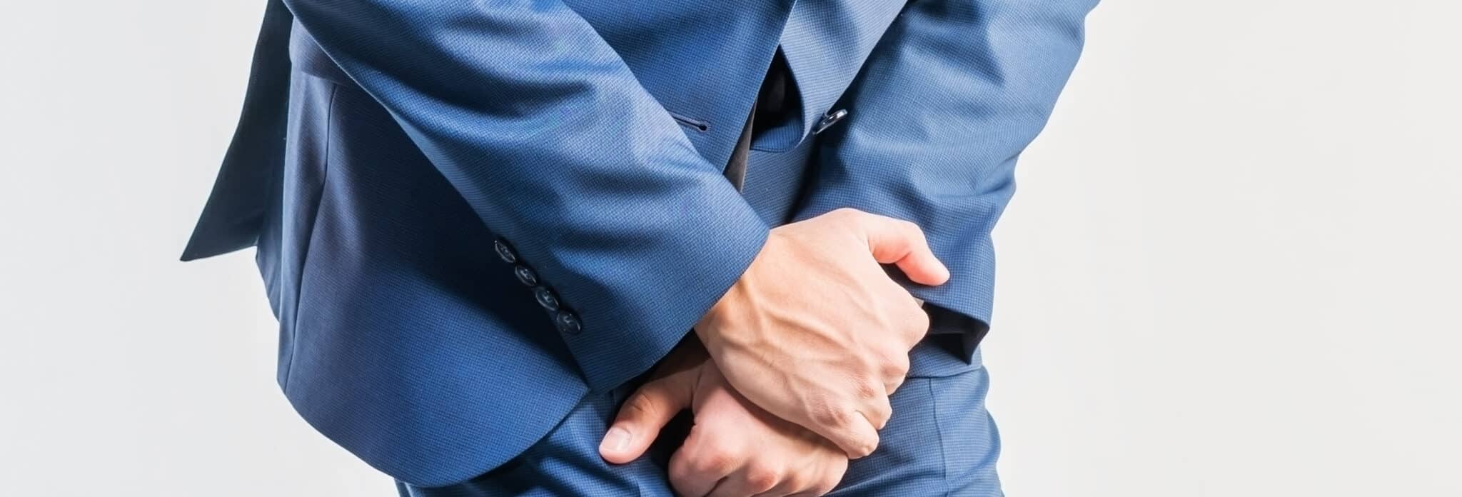 Young attractive man in a blue suit  feels pain on a white background. Isolated