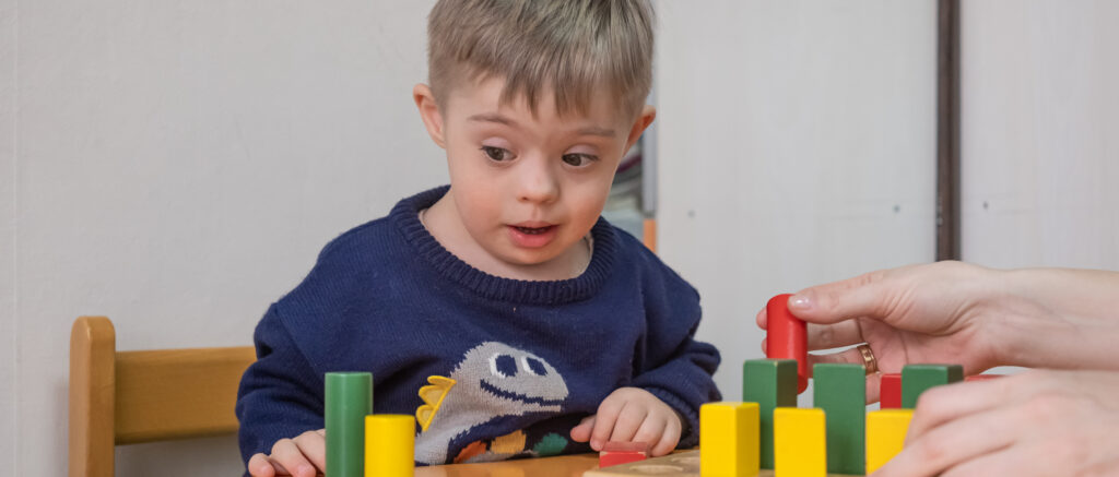 boy with living down syndrome enjoying playtime with toys rehabilitation center 1 LIV Hospital