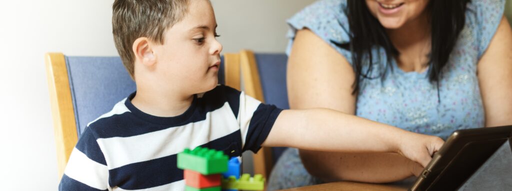 child with down syndrome playing with colorful blocks tablet assisted by woman engaging playtime with blocks technology fostering learning mother son family moment 1 LIV Hospital