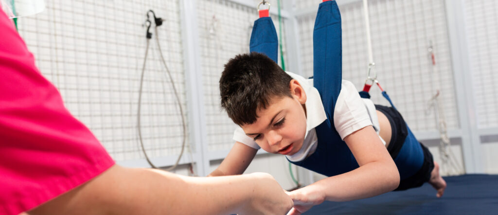 physical therapy room physically disabled child exercising with elastic cords 2 LIV Hospital