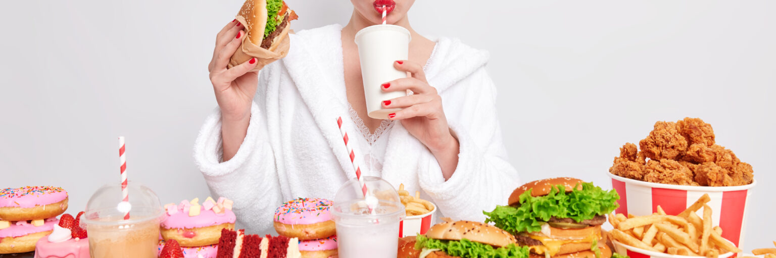 unhealthy nuttrition concept housewife with red manicure lips domestic bathrobe towel head drinks soda eats junk food 2 LIV Hospital
