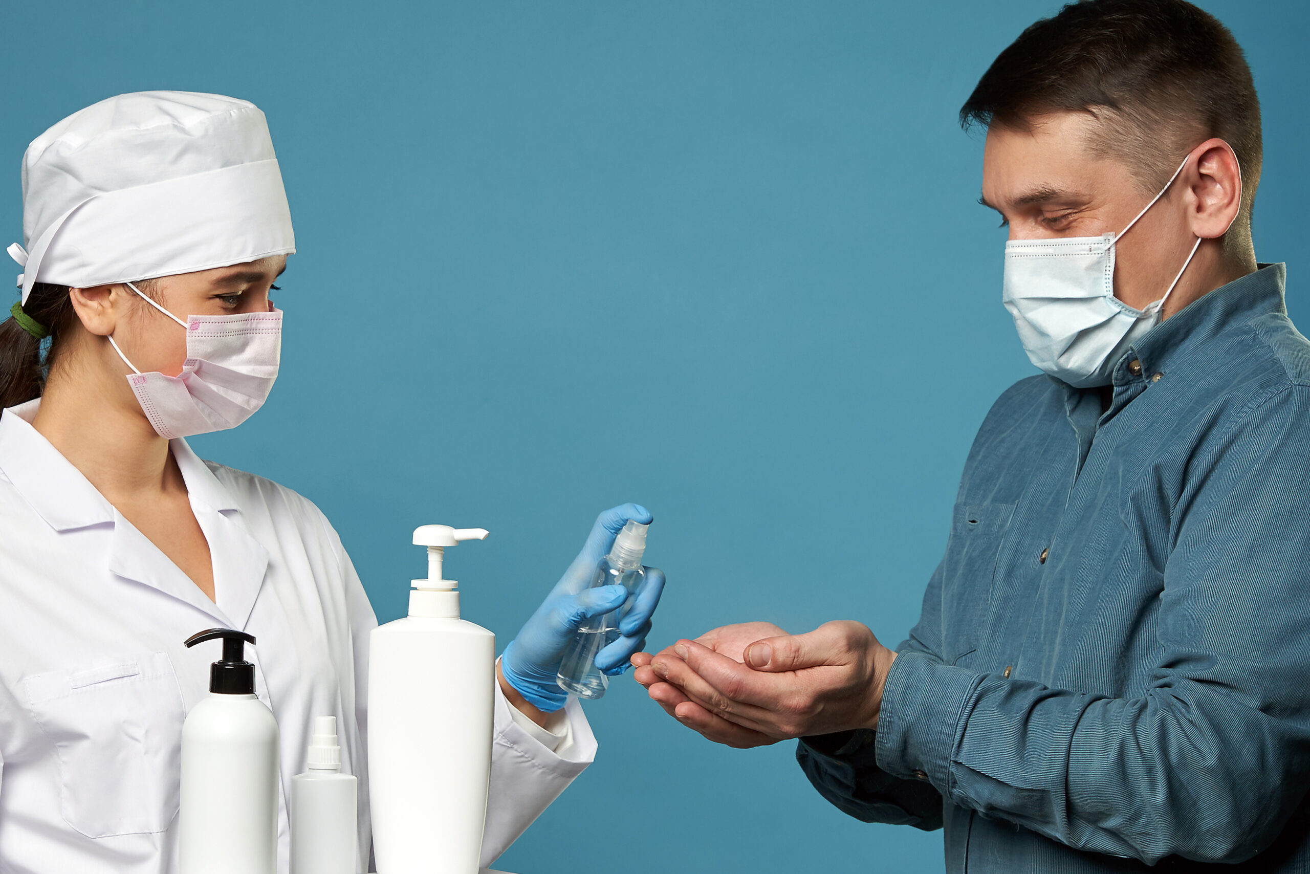 doctor applying antibacterial spray patient hands blue wall scaled LIV Hospital