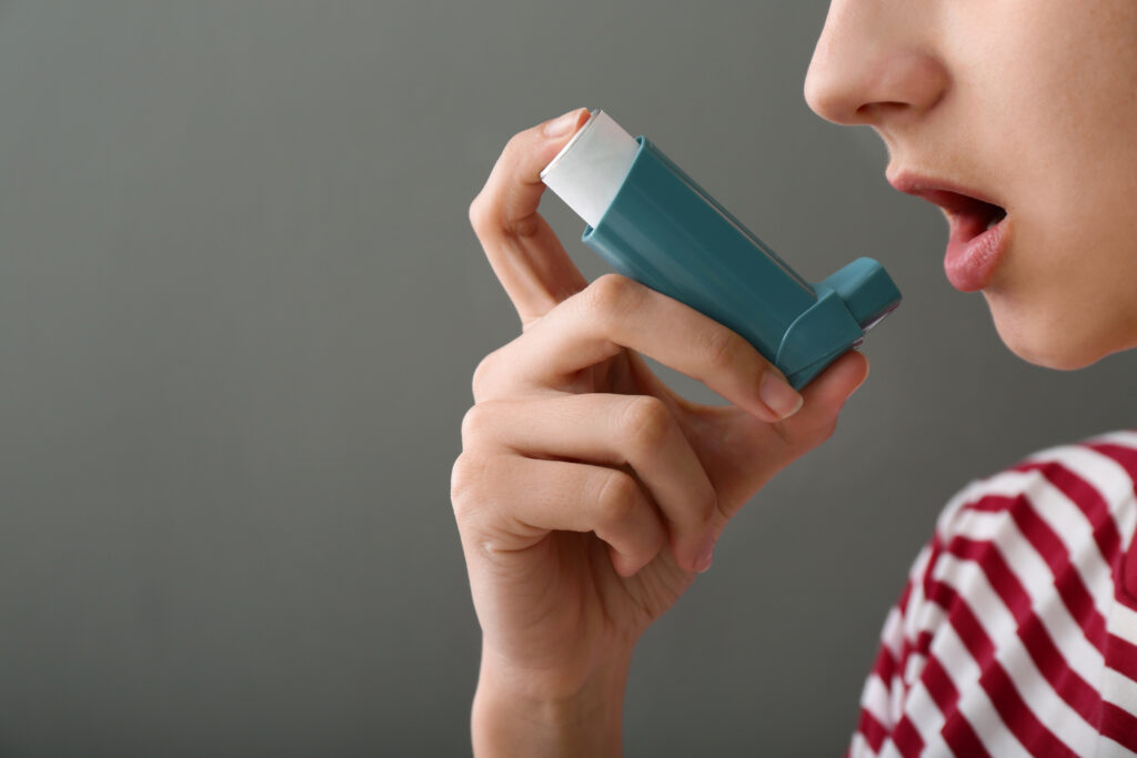young woman using inhaler against asthma grey LIV Hospital